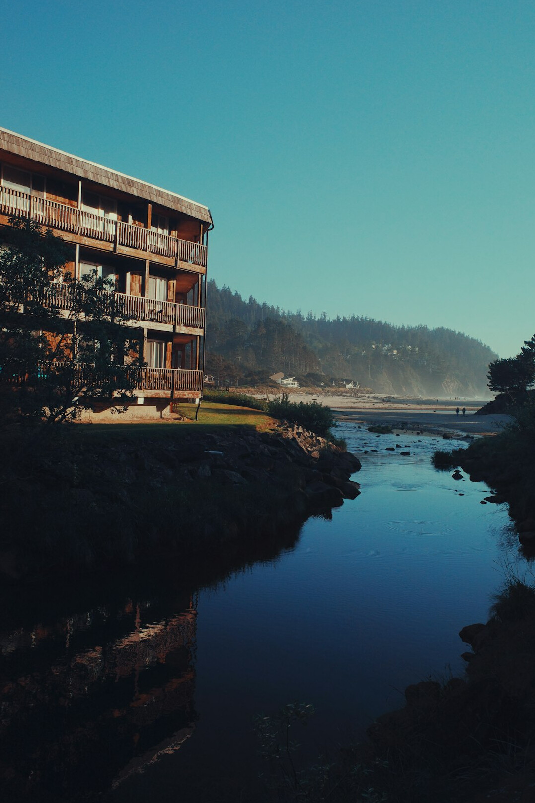 River mouth meeting the ocean with modern homes along the bank