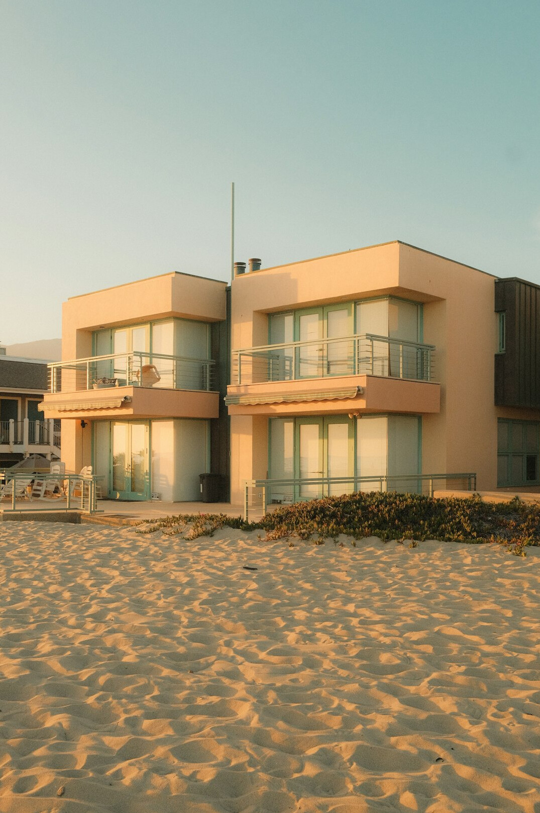 Modern minimalist oceanfront villa with large glass windows at golden hour